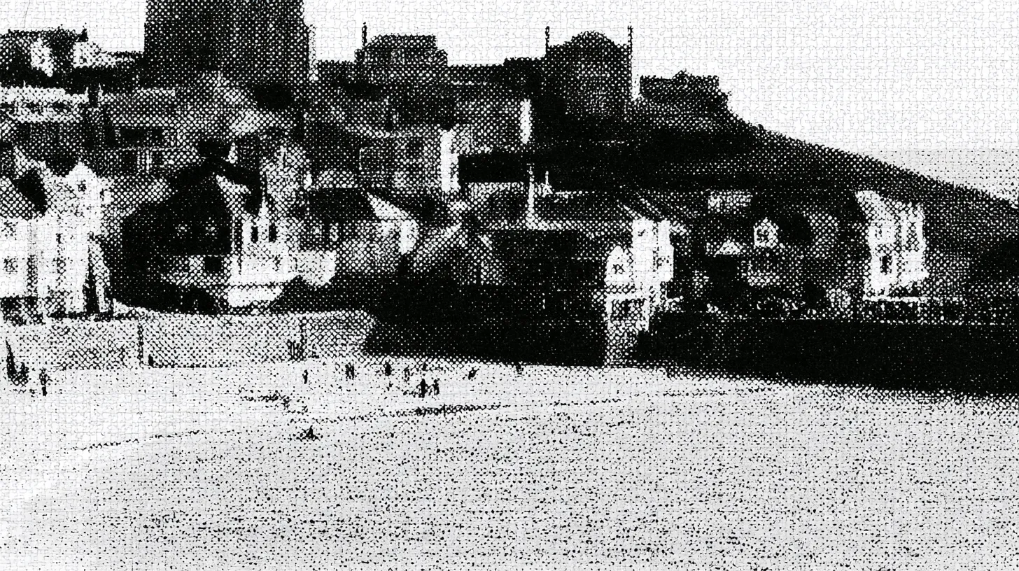 A half-tone view of a seafront town's harbourside buildings and headland, rendered in coarse newsprint dots.